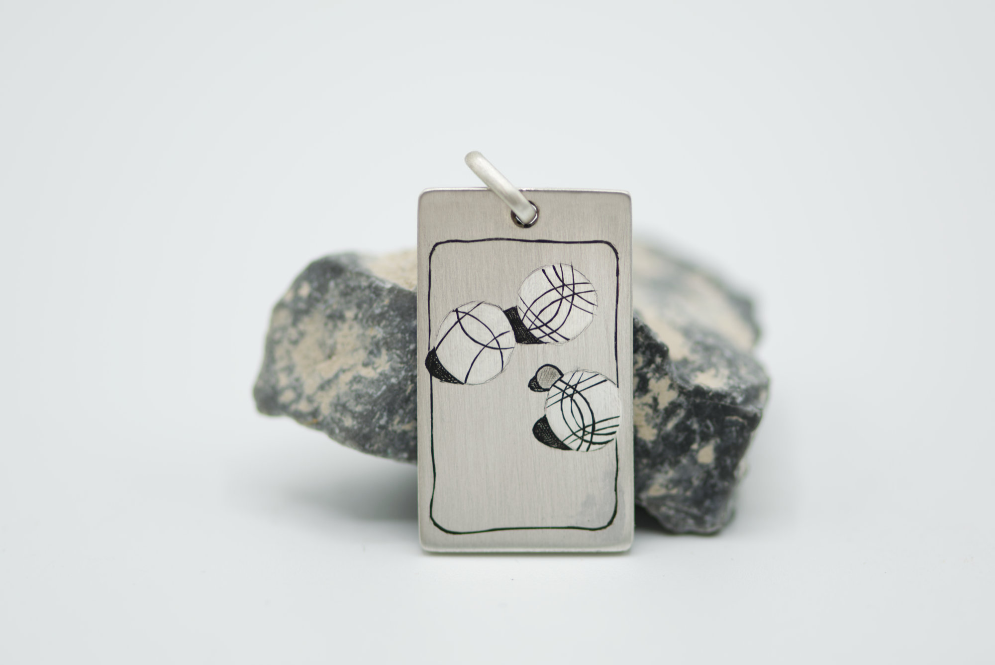 Partie de pétanque gravée à la main sur un pendentif en argent