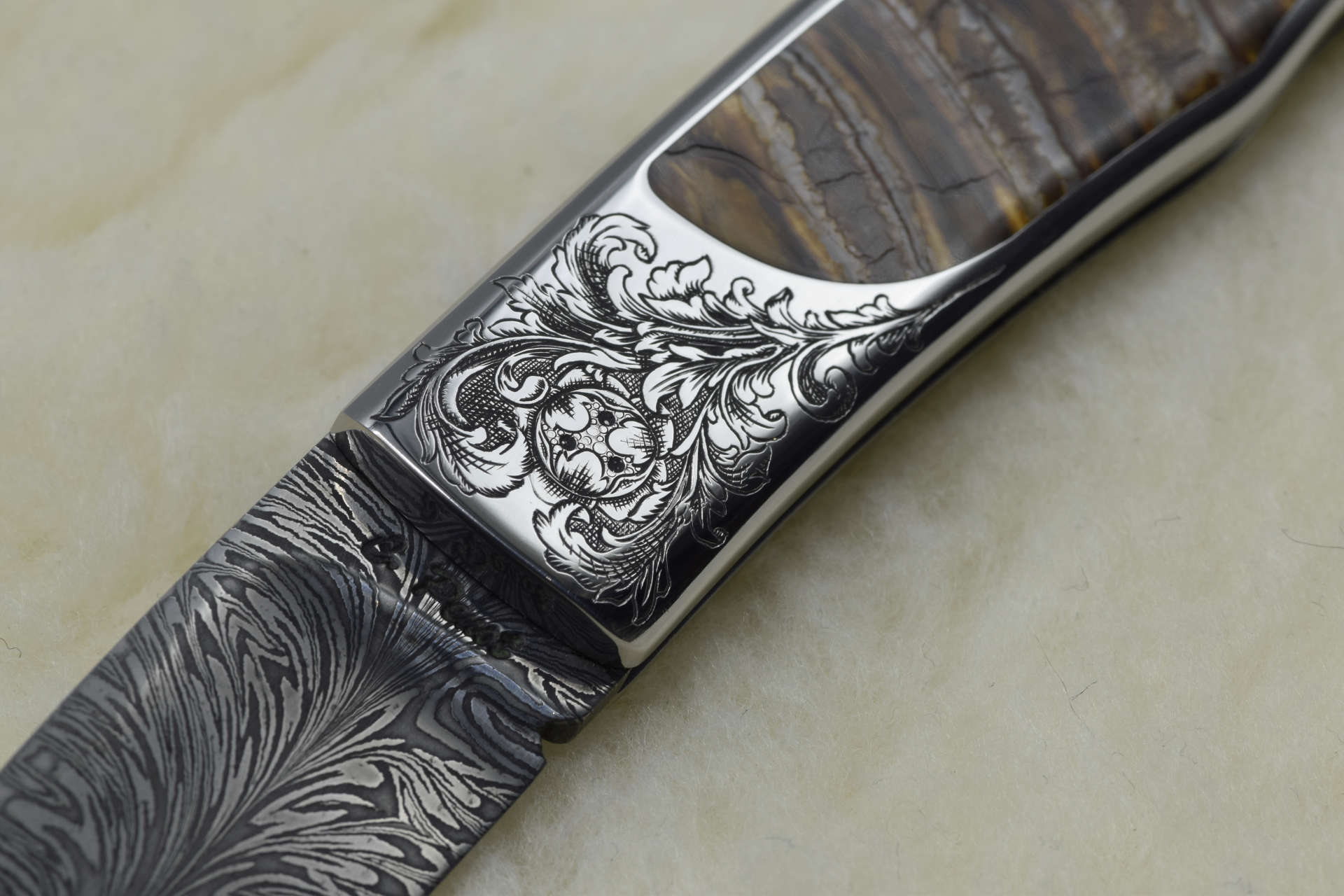 Gros plan recto : gravure de motif d'acanthe classique sur mitre de couteau inox, taille douce
