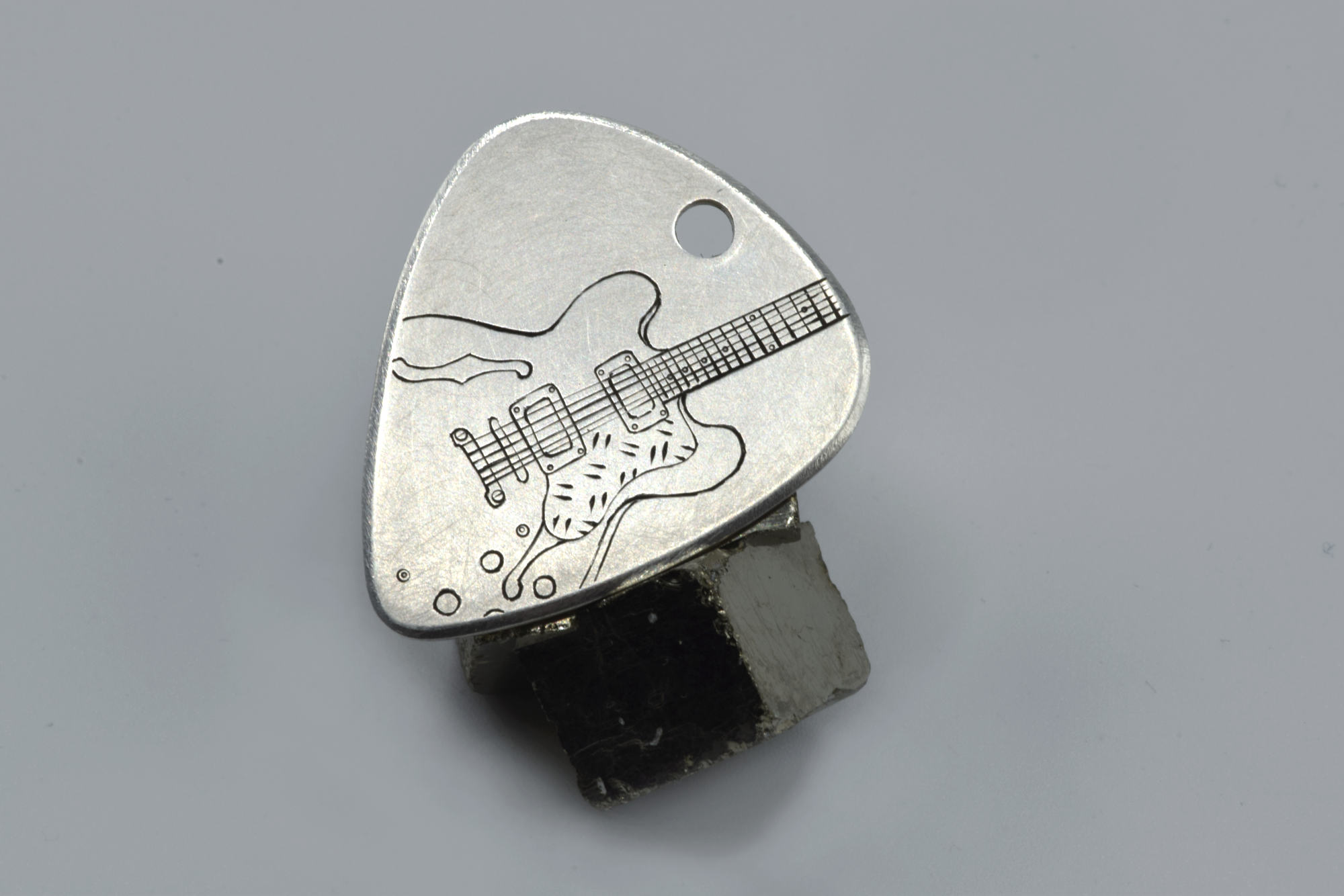 Médiator en argent transformé en pendentif sur mesure, gravé d'une guitare
